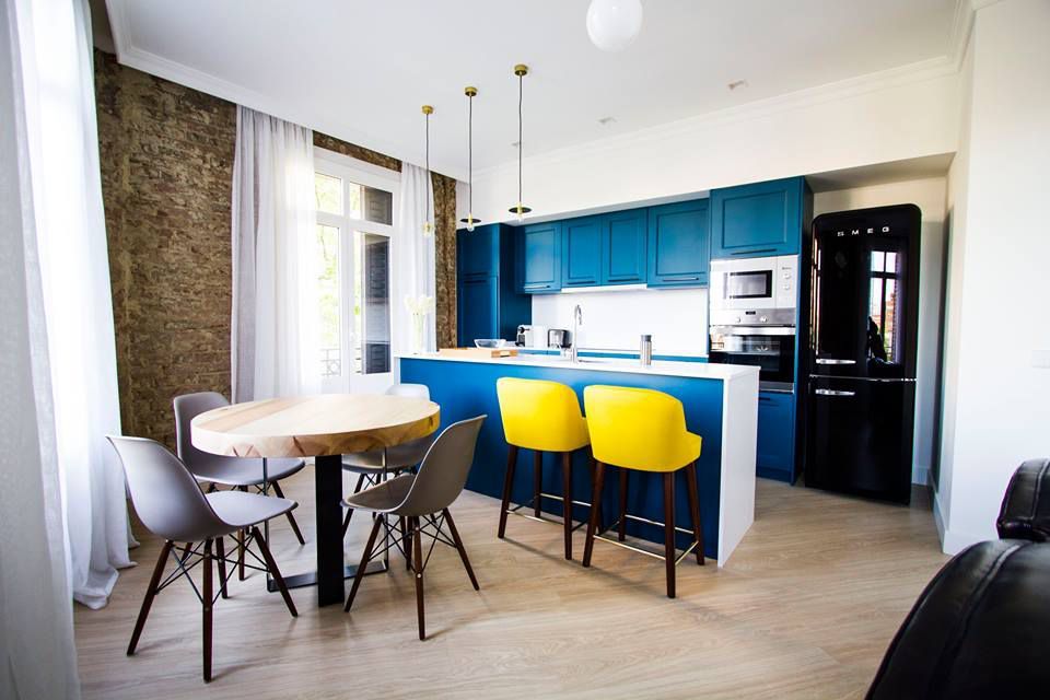 Cocina moderna con mesa de comedor y mesa alta con muebles en azul