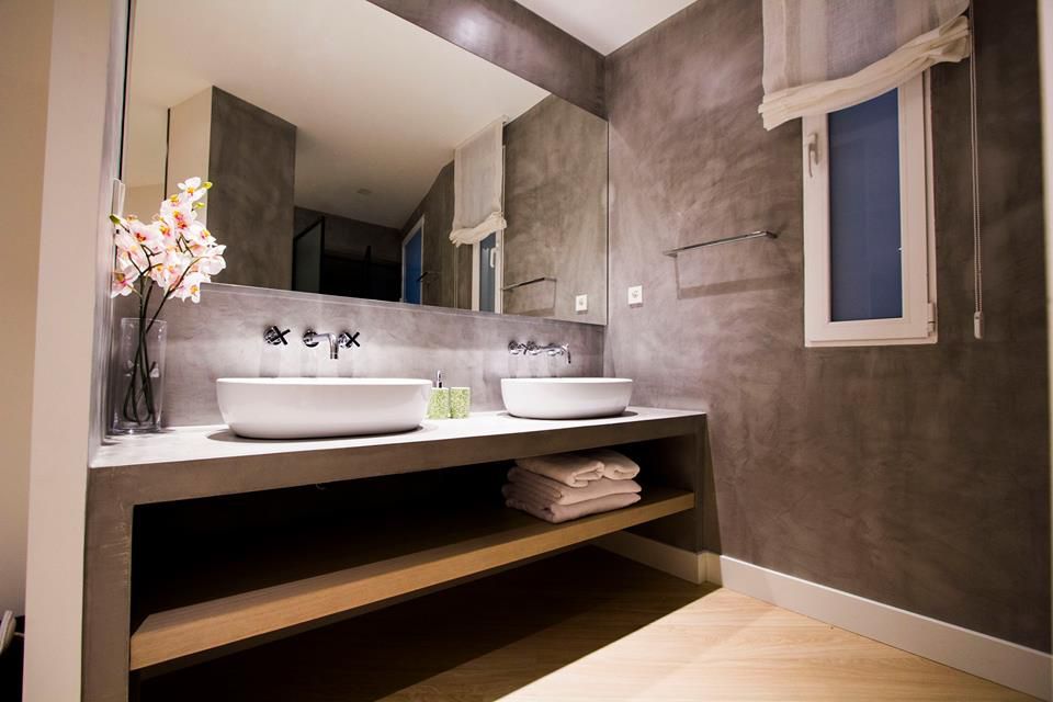 Baño con dos lavabos redondeados a la izquierda con paredes grises