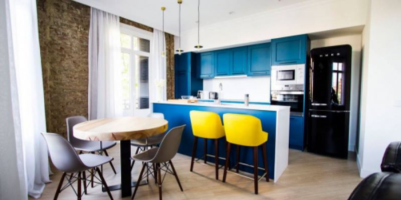 Cocina moderna con mesa de comedor y mesa alta con muebles en azul
